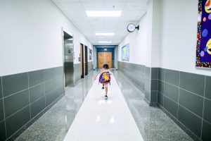 Legionella Prevention Plan in Schools - image of school hallway, and child running to class.